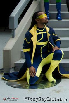 a man in a yellow and blue outfit sitting on the ground next to some stairs