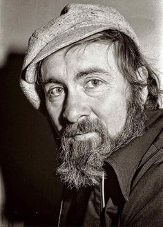 black and white photograph of a man with a beard wearing a hat looking at the camera