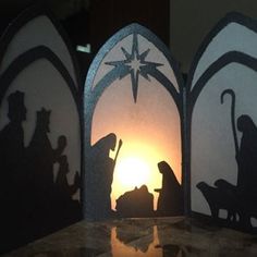 three paper cut nativity scene with the birth of jesus and baby jesus in silhouette