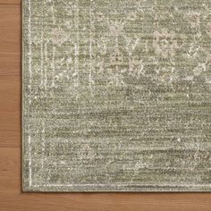 an area rug on top of a wooden floor with white and green designs in the middle