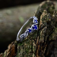 a silver ring with blue stones sitting on top of a tree