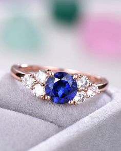 a blue and white diamond ring with three stones on the side, sitting on top of a