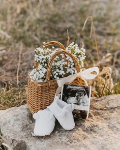 a basket filled with baby's breath sitting on top of a rock next to flowers