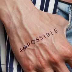 a person's hand with the word impossible tattooed on it