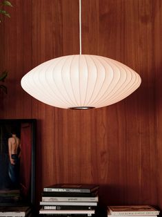 a white light hanging from a wooden wall next to books and a framed photograph on a table