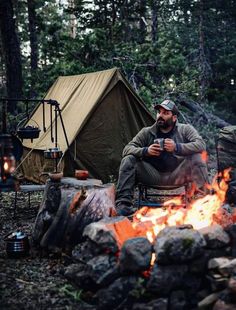 a man sitting in front of a campfire