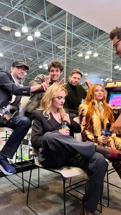 a group of people sitting around each other in front of a video game screen with one person holding a microphone