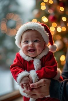 a baby in a santa suit is being held by someone