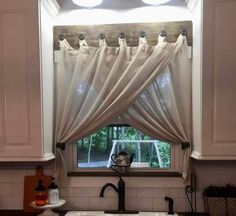 a kitchen sink under a window with curtains