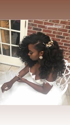 a woman sitting on top of a white chair wearing a dress and flower in her hair