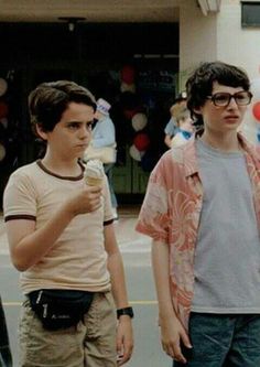 two young men standing next to each other holding an ice cream cone in their hands