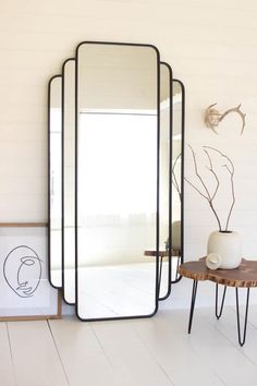 a large mirror sitting on top of a wooden table next to a vase and plant