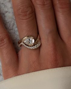 a woman's hand with a diamond ring on top of her finger and an engagement band