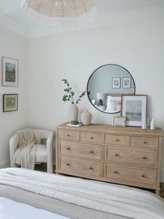 a bedroom with a bed, dresser and mirror on the wall next to each other