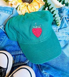 A embroidered strawberry on a green base ball cap. Casual Brimmed Hat With Embroidered Logo, Cute Summer Dad Hat, Cute Dad Hat For Summer, Trendy Hats With Curved Brim, Trendy Brimmed Cotton Baseball Cap, Playful Adjustable Dad Hat Baseball Cap, Playful Cotton Baseball Cap For Spring, Cute Cotton Baseball Cap For Summer, Cute Summer Cotton Dad Hat