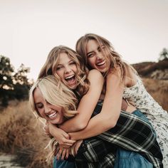 three women hugging each other in the middle of a field