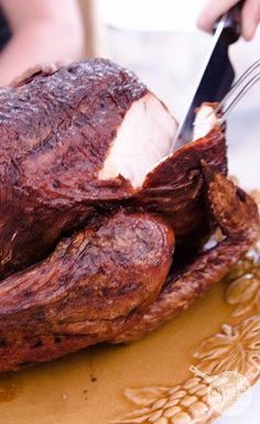 a person cutting up a large piece of meat on a plate with a knife and fork