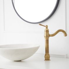 a white bowl sitting on top of a counter next to a mirror and faucet