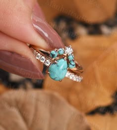 a woman's hand holding a ring with turquoise stones and diamonds on top of it