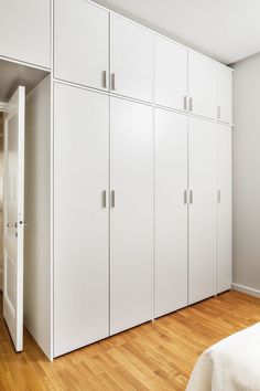 an empty bedroom with white cabinets and wood floors