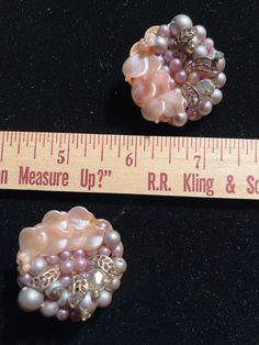 two pieces of jewelry sitting next to a ruler