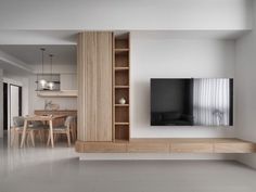 a living room filled with furniture and a flat screen tv mounted on a wall next to a wooden shelf