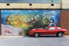 a red sports car parked in front of a wall with route 66 painted on it