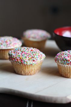 several cupcakes with sprinkles are sitting on a table next to a bowl