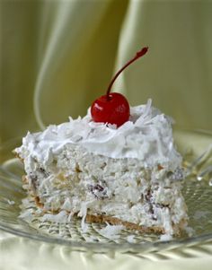 a piece of cake on a glass plate with a cherries garnish and white frosting