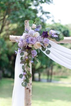 a cross decorated with flowers and greenery on the side of a wooden pole for an outdoor wedding ceremony