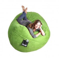 a woman laying on top of a green bean bag chair next to a cell phone