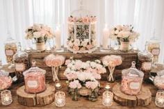 a table topped with lots of vases filled with pink flowers and candles next to wooden slices