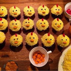 cupcakes decorated with yellow frosting and chicken heads are arranged on a table