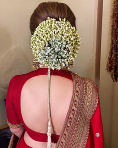 the back of a woman's head with flowers in her hair, wearing a red saree