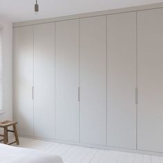 an empty bedroom with white closets and a bench