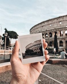 a person holding up a polaroid in front of the colossion, rome