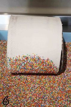 a roll of toilet paper with sprinkles on it in front of a machine