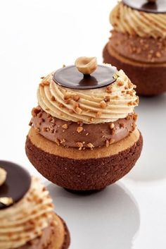 three cupcakes with chocolate frosting and nuts on top