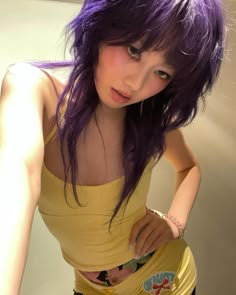 a young woman with purple hair is posing for the camera while wearing a yellow tank top