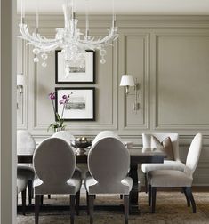 a dining room table with white chairs and chandelier