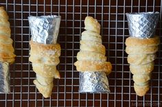 four pastries wrapped in aluminum foil lined up on a wire rack