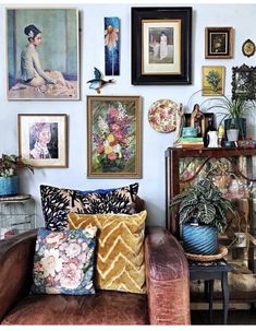 a living room filled with furniture and pictures on the wall next to a table full of plants