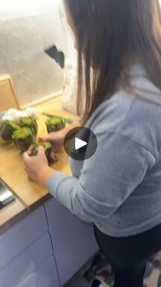 a woman cutting up lettuce on top of a wooden counter next to a stove