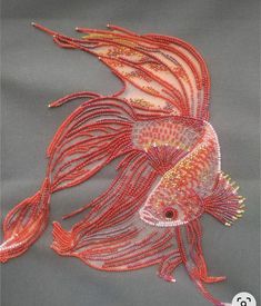 a fish made out of beads on a gray background