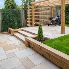 an outdoor patio area with steps, grass and shrubbery in the back ground near a barbecue grill