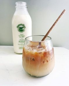 an iced drink with ice and cinnamon in a glass next to a bottle of milk