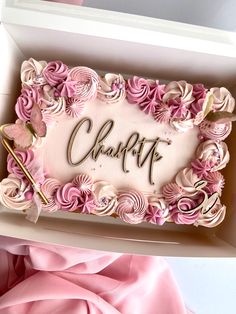 a cake in a box with the word charlotte written on it and pink flowers all around