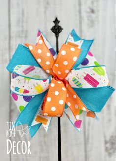 an orange and blue polka dot bow on a black stake