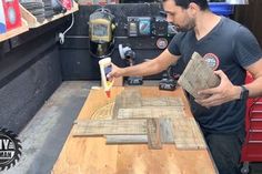 a man is working on some wood at a table