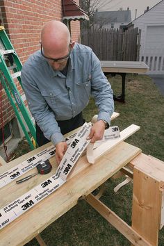 a man working on some wood with a pair of scissor and tape measures